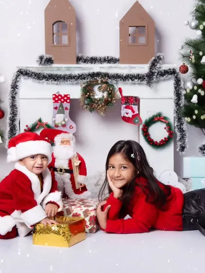 Siblings enjoying the holiday spirit together in our snowy Christmas scene with presents and trees.