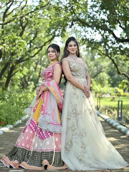 Two contrasting styles side-by-side. A vibrant pink and yellow patchwork lehenga stands next to an elegant pastel green gown, showcasing options for different tastes.