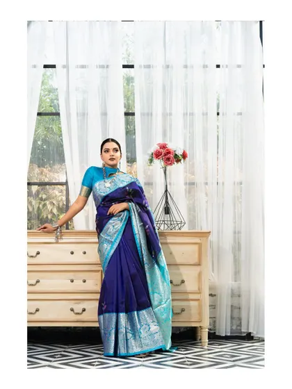 An elegant indoor portrait. The combination of the rich blue Kanchipuram saree, the classic furniture, and soft window light creates a sophisticated and timeless look.