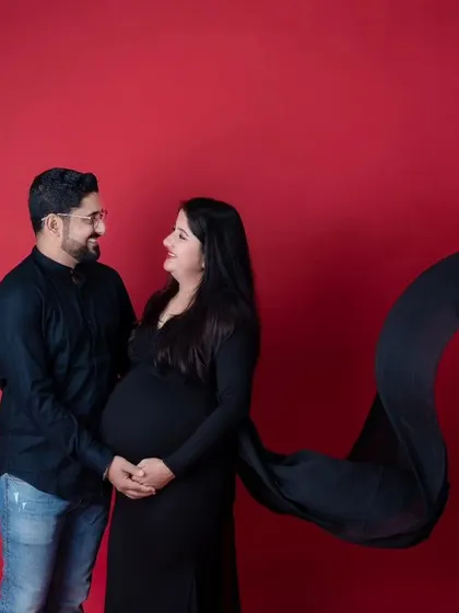 A duplicate of image 18, showing a striking couple's maternity photo set against a bold red backdrop.