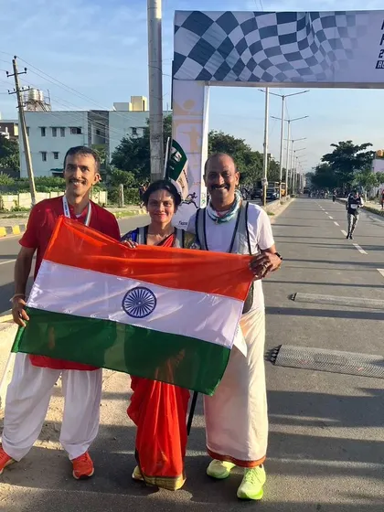 A family of runners poses with the national flag at the finish line, celebrating their shared achievement.