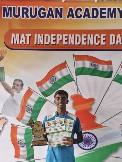 Here is Jagadeep, our Under 16 Champion at the MAT Independence Day Cup. He is holding his trophy and certificate in front of the tournament banner, a testament to his dedication.