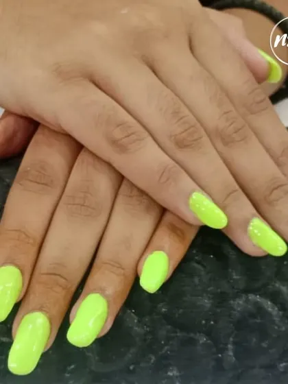 A vibrant and clean set of neon yellow nails done by a student. It shows their mastery of shaping and smooth application.