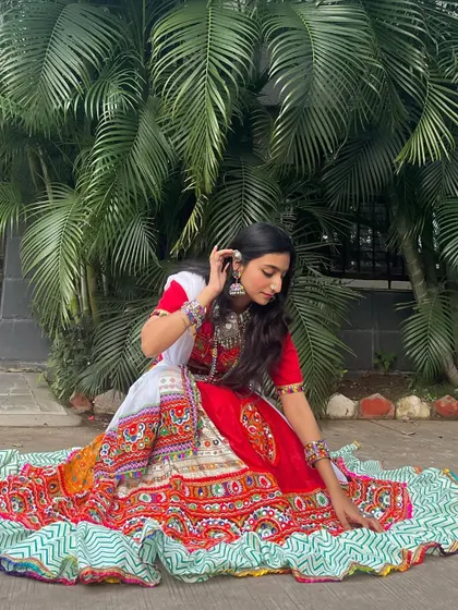 This red and white chaniya choli has a beautiful spread, with a green and white patterned border. It's a classic and graceful choice for Garba.