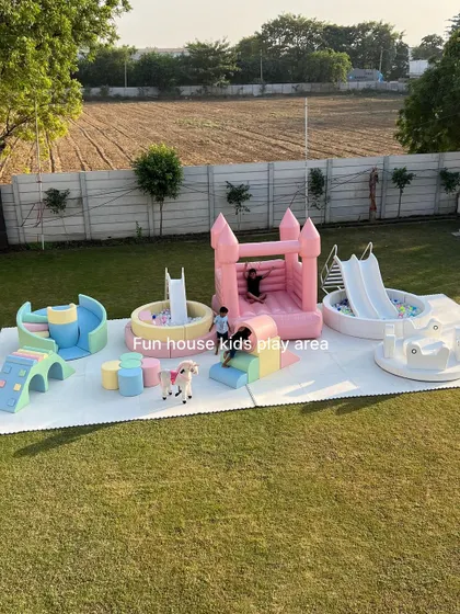A large-scale outdoor setup featuring our new pastel play area, a pink bouncy castle, a white ball pit, and a merry-go-round for ultimate fun.