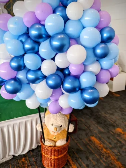 A hot air balloon made of blue, purple, and white balloon's with a teddy bear passenger, adding a whimsical touch to the party.