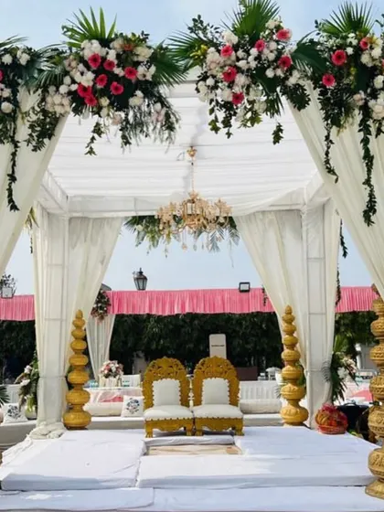 A classic white wedding mandap (Bedi) decorated with hanging floral strings and traditional golden props, perfect for an elegant outdoor ceremony.