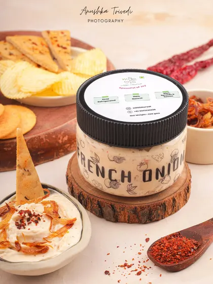 A jar of French Onion dip, styled with chips and crackers to show how the product can be enjoyed.