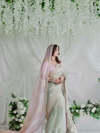 The bride, Hina Khan, looks ethereal against the backdrop of white florals and draped fabric. The decor was designed to complement her grace and the soft elegance of her attire.