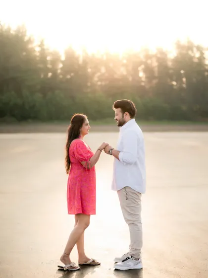 The couple holds hands and walks on the beach at sunset, a classic and romantic scene from their pre-wedding photoshoot.