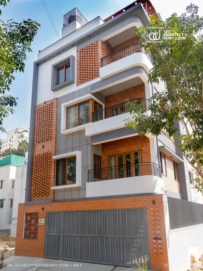The completed facade of the Akshaynagar residence, featuring a unique blend of brick jali panels, curved white balconies, and grey accents. This project was featured in The Architect's Diary.