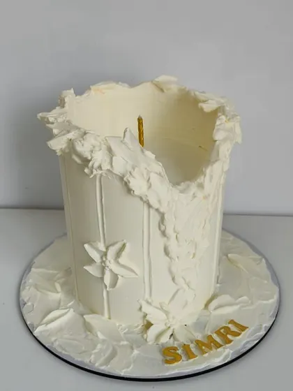 A special candle-inspired cake for a loyal client. This design features textured white frosting to resemble a melting candle, personalized with the name "Simri" in gold.
