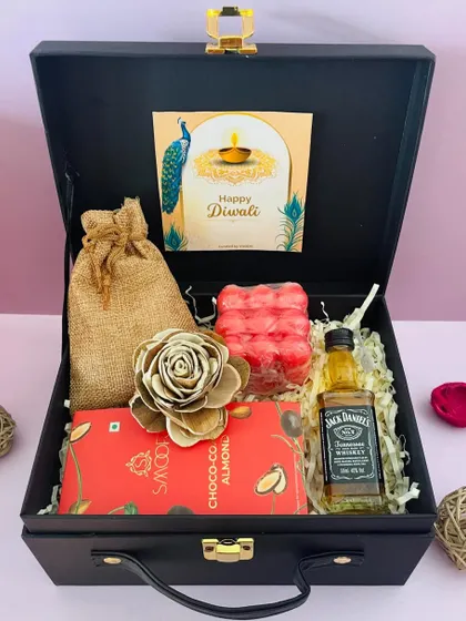 This black suitcase hamper is perfect for a Diwali party host, featuring a miniature Jack Daniel's, a chocolate bar, and a decorative sola wood flower.