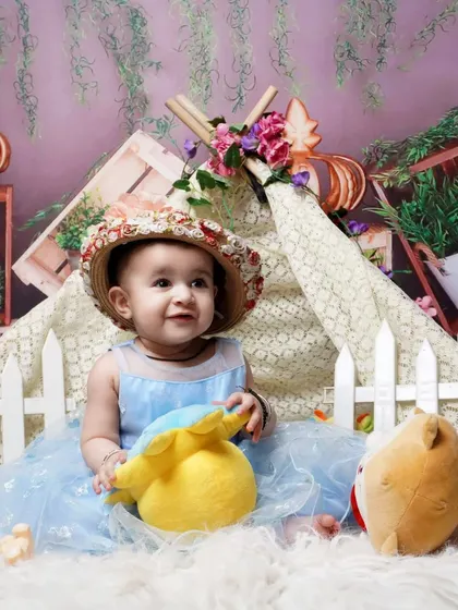 A cute toddler photoshoot with a garden tent theme. I use props like a picket fence, stuffed animals, and flowers to create a playful outdoor scene indoors.