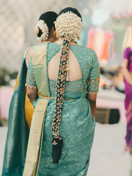 A detailed look at a traditional South Indian bridal hairstyle. This long braid is intricately decorated with gajra and golden accessories, a true statement piece for any bride.