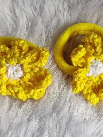 A pair of bright yellow floral scrunchies. These are handmade with soft yarn and are gentle on the hair while adding a pop of color.