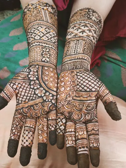 A classic full-hand mehendi with filled fingertips, a popular choice for a traditional look. The design features a dense mix of jaali patterns and delicate swirls.