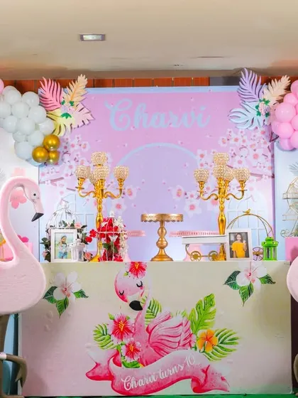 A closer look at the flamingo party dessert table. The setup includes two large flamingo props, elegant candelabras, and a beautiful pastel and gold color scheme.