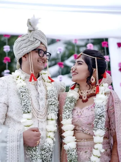 The look of love and happiness between a newly married couple, adorned with beautiful white rose garlands.
