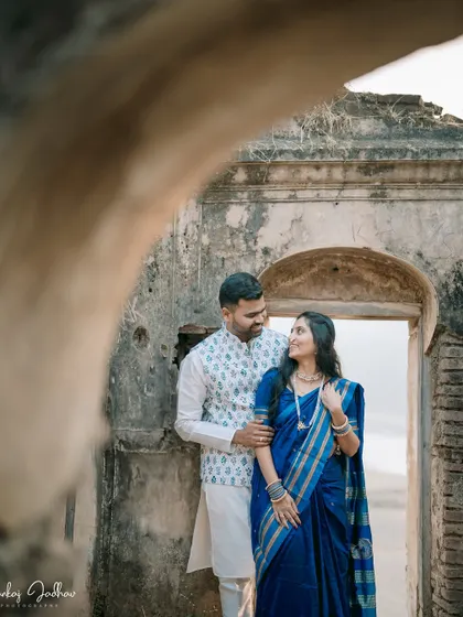 A glance of love, framed by ancient stone. This shot uses a natural frame to create depth and focus on the couple's interaction during their pre-wedding shoot.