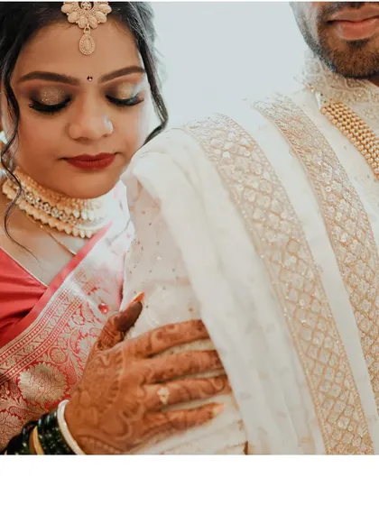 A detail-oriented shot focusing on the bride's henna-adorned hand on the groom's sherwani. This captures the texture, tradition, and tenderness of the moment.