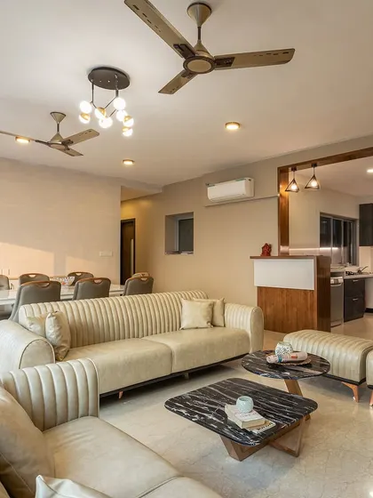 The living room is furnished with plush, cream-colored leatherette sofas and a black marble coffee table, creating a look of sophisticated comfort.