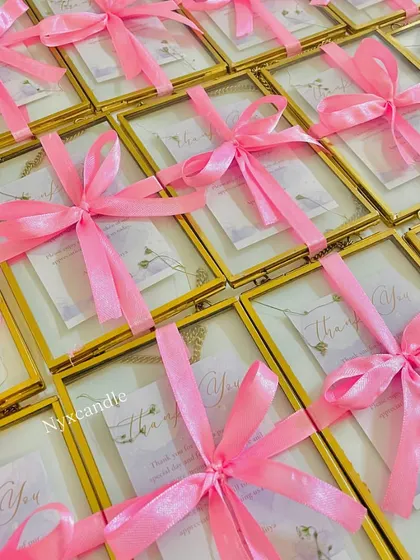 A beautiful array of our brass photo frame wedding favors, each tied with a pink ribbon and ready to be gifted.