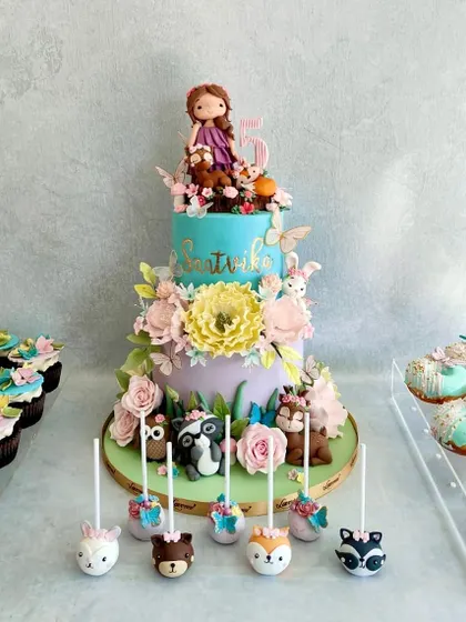 This woodland-themed dessert table for Saatvika's birthday was so elaborate and beautiful. The cake is adorned with sugar flowers and cute woodland creatures, and we made matching cake pops, donuts, and cupcakes.