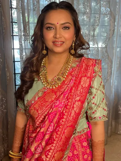A stunning look in a pink and green silk saree, with soft curls and glowing makeup. Her natural eye color is the star of the show.