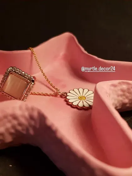 A close-up of the pink starfish tray, showing the daisy necklace and ring it holds.