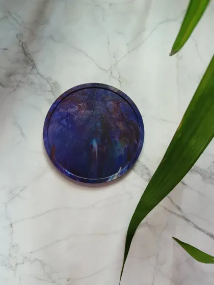 This deep blue coaster has a mesmerizing, galaxy-like pattern. It's a small piece of art for your table, handcrafted from plastic waste.