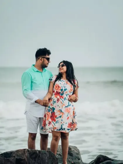 A sweet moment of connection on the rocks by the sea. This pre-wedding photo captures the calm and intimacy of a beach setting.