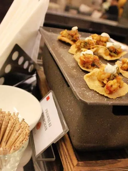 These crispy papdi canapés are topped with a spicy prawn mixture and a dollop of sour cream. They are a perfect example of our Indian fusion appetizers, ideal for adding a local touch to your event.