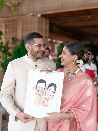 A fun moment from an engagement party where the couple holds up a caricature of themselves, sharing a genuine smile.