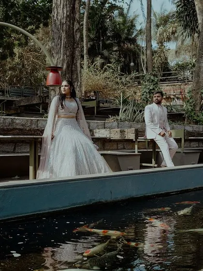 A wide, cinematic shot of a couple at their outdoor venue, seated near a koi pond. This image showcases the beauty of the wedding location.