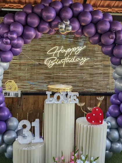 A stylish 31st birthday party with a purple and silver balloon arch. The setup includes marquee numbers and a 'Love' prop on the cake stand.