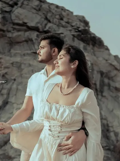 A powerful, cinematic pose against a dramatic rock formation. The couple looks towards the future, their hands joined, embodying strength and unity.