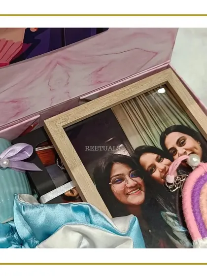 A 'lilac beauty' birthday hamper for a girl. This pink marble box is filled with a photo frame, a blue ceramic mug, and satin scrunchies.
