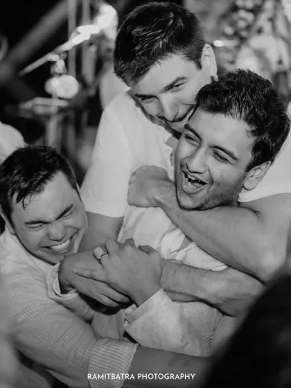 A candid black and white photo capturing the pure joy and camaraderie between the groom and his friends during the party.