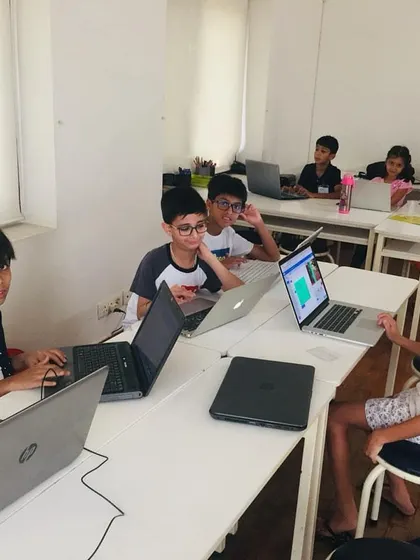 A typical day at our summer camp, with young coders collaborating and learning from each other in a bright, stimulating classroom. We encourage teamwork and peer-to-peer learning as part of our educational process.