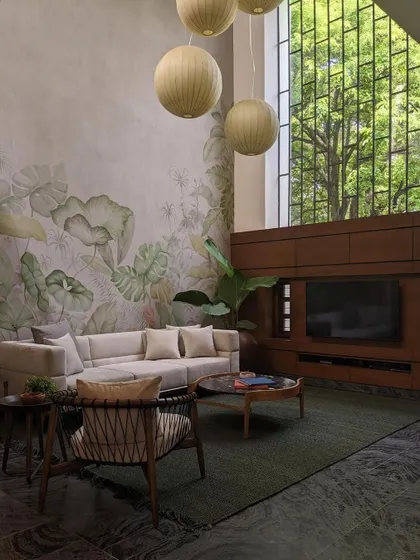 The living room is defined by a double-height, hand-painted mural depicting local foliage. This artistic feature brings the essence of the garden indoors, complemented by spherical pendant lights and comfortable, modern furniture.