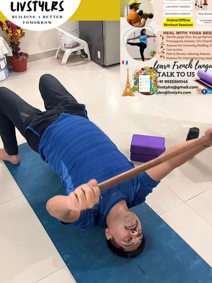A client uses a stick for a chest-opening stretch on the floor. This simple prop can significantly improve shoulder mobility and posture, a key focus in our yoga sessions.