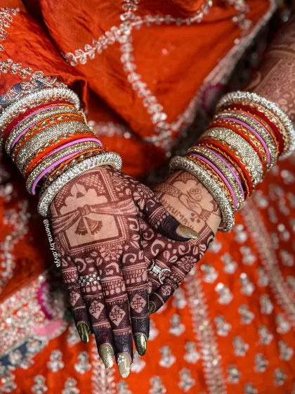 The back of the hands after the henna has stained. The deep color looks stunning against the bride's colorful bangles and traditional attire.