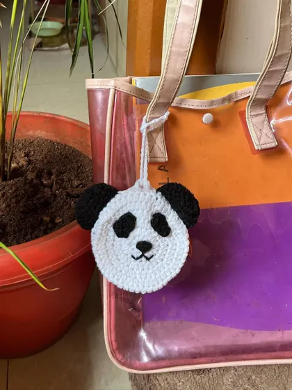 The panda pouch hanging from a tote bag, demonstrating how it can be used as a cute bag charm.