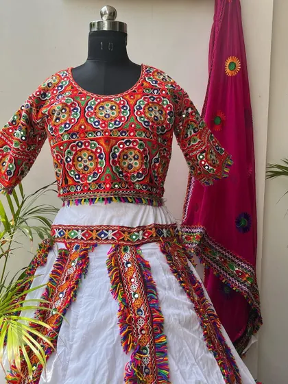 A classic white chaniya choli with colorful embroidery and a bright pink dupatta. This is a timeless and elegant choice for Navratri.