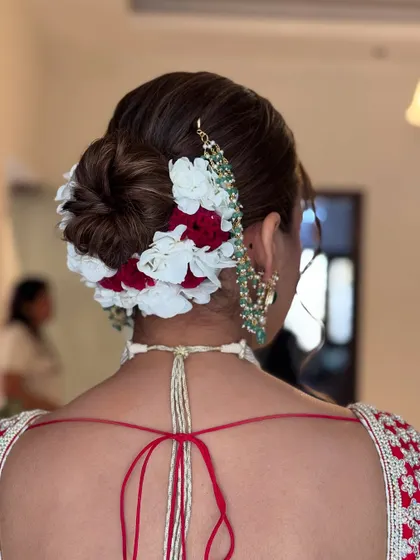 This bridal bun combines red and white flowers for a classic and vibrant look. The flowers are carefully placed around a neatly twisted bun, creating a beautiful frame that complements the traditional red and white wedding attire.