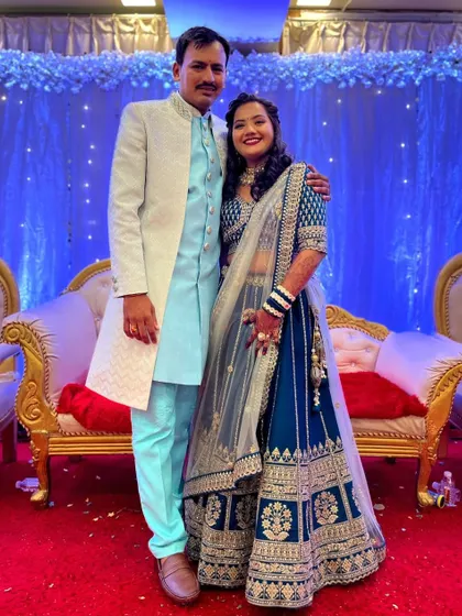 A couple posing at their event. He looks dapper in a light blue and white sherwani that coordinates beautifully with her teal and silver lehenga.