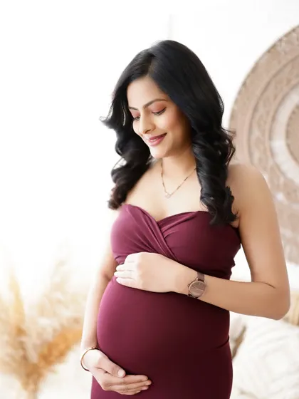 A serene and beautiful portrait. The mom-to-be cradles her bump, her expression full of love and anticipation.