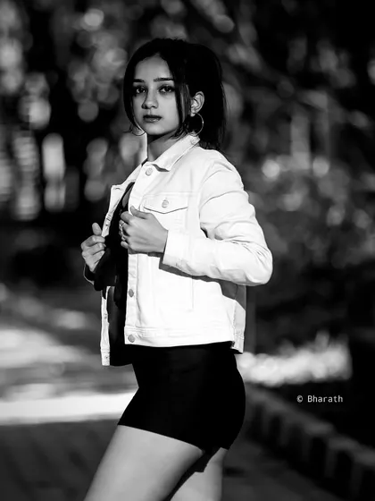 A full-length black and white portrait on a paved path. The strong lines and contrast create a bold, graphic image.