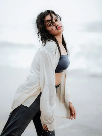 This image captures a strong, confident pose against a cloudy sky. The wet hair and casual styling give it a raw and authentic feel.